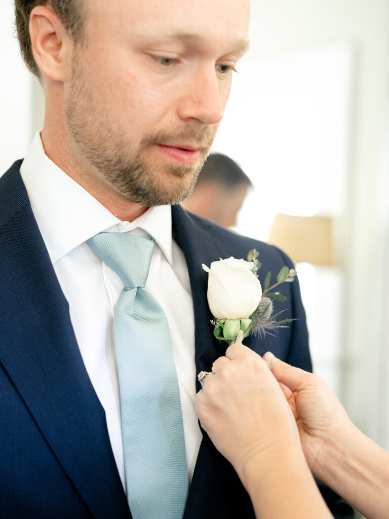 groom getting flower pinned to lapel
