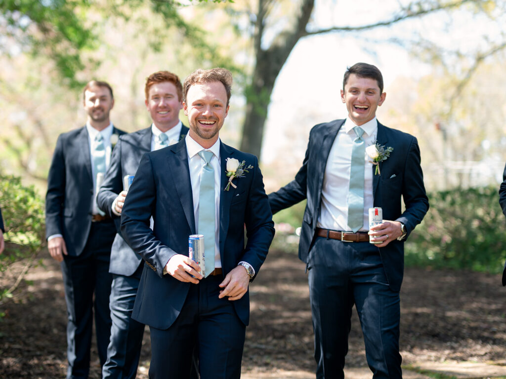 groomsmen walking and laughing holding beers and walking away