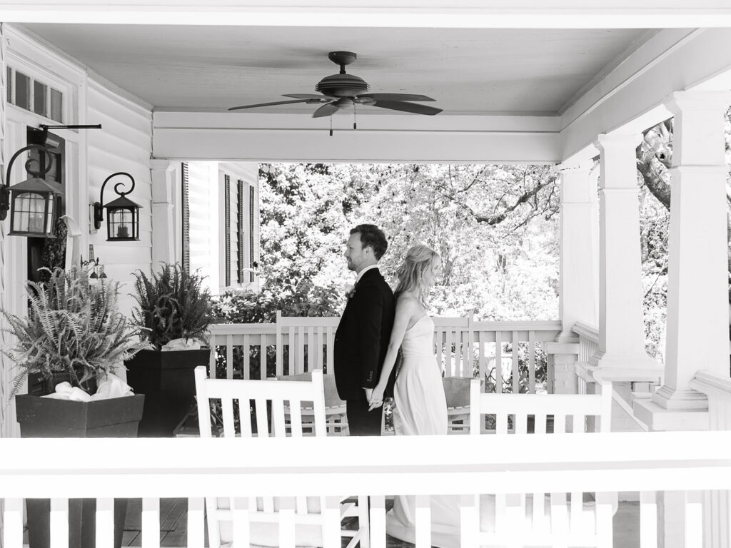 black and white image from afar of couple on the porch.