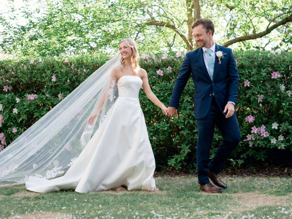 bride and groom walkking hand in hand with veil trailing behind